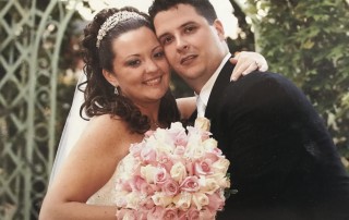 Happy couple on wedding day, holding pink roses.